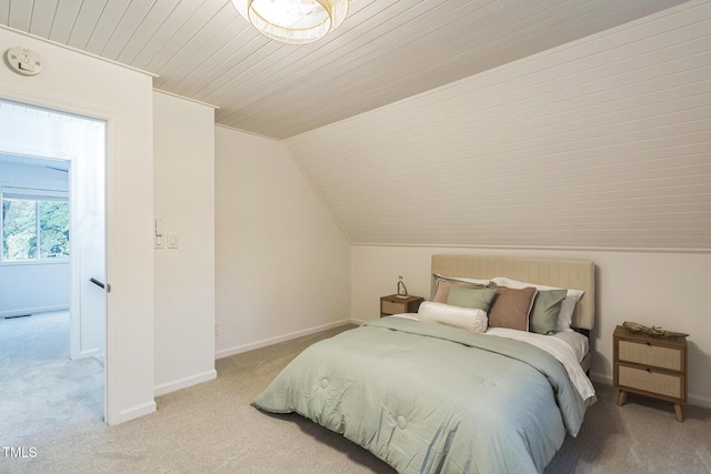 bedroom featuring light carpet, lofted ceiling, and baseboards