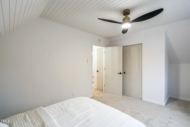 bedroom featuring light carpet, ceiling fan, baseboards, wooden ceiling, and a closet