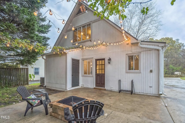 rear view of property featuring a fire pit, a patio area, and fence