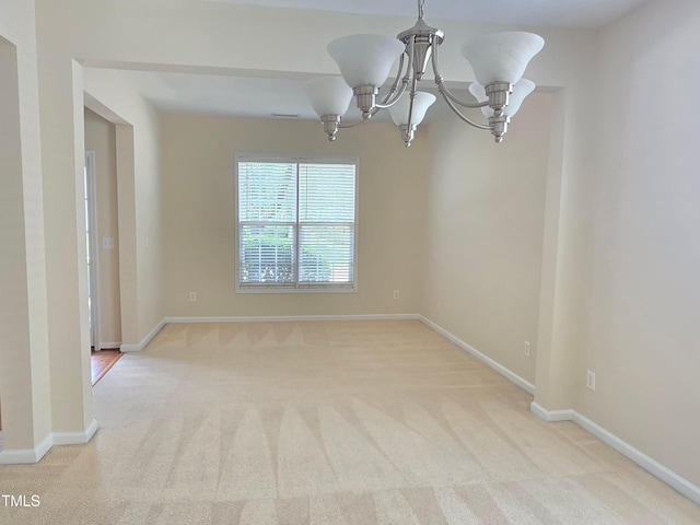 unfurnished room featuring carpet, a chandelier, and baseboards