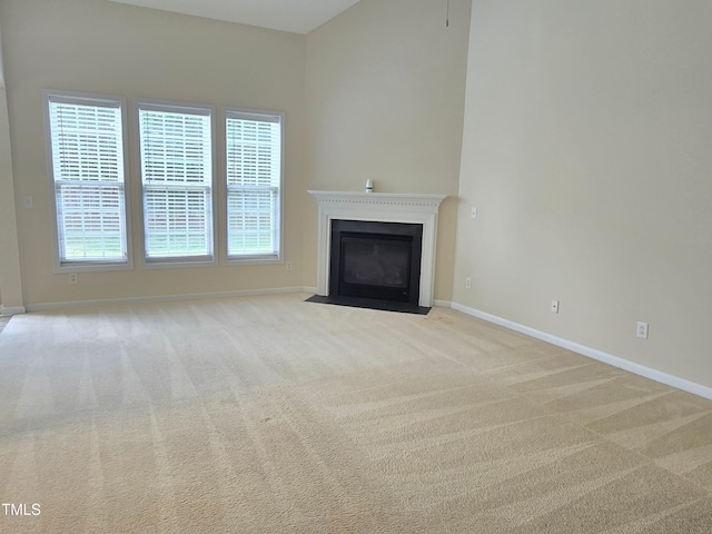 unfurnished living room with baseboards, carpet flooring, and a fireplace with flush hearth