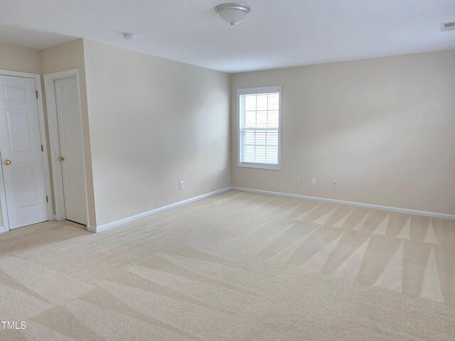 unfurnished room with light carpet and baseboards