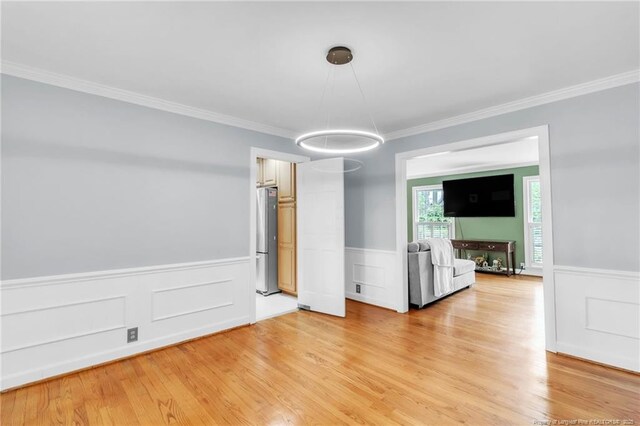 503 Charleston Pl, Fayetteville, NC 28303 - unfurnished dining area featuring a wainscoted wall, light wood-style flooring, ornamental molding, and a decorative wall