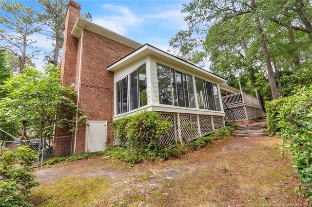 503 Charleston Pl, Fayetteville, NC 28303 - view of home's exterior with brick siding, a chimney, a sunroom, and fence