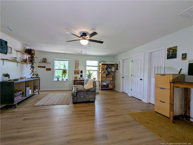 living area featuring a ceiling fan, wood finished floors, and baseboards
