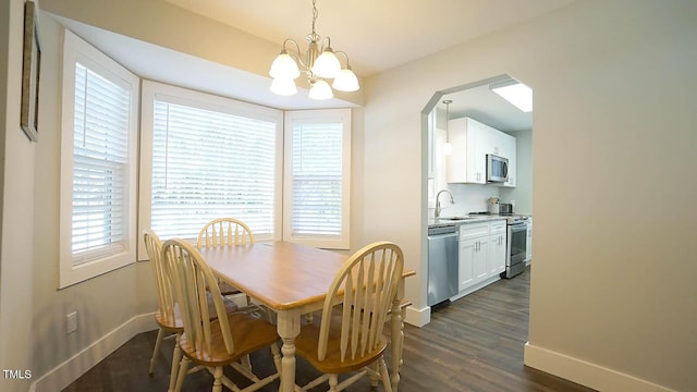 dining space with a chandelier, baseboards, dark wood-style flooring, and arched walkways