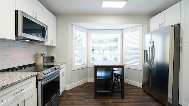 kitchen with stainless steel appliances, dark wood finished floors, decorative backsplash, and baseboards
