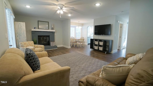 living room featuring ceiling fan, baseboards, dark wood finished floors, a brick fireplace, and recessed lighting