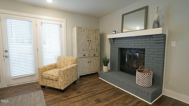 sitting room featuring a brick fireplace, wood finished floors, and baseboards