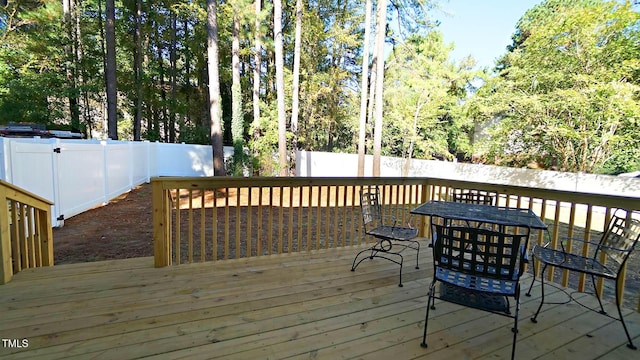 wooden terrace with a fenced backyard and outdoor dining area