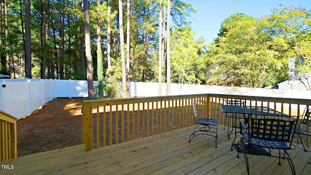 wooden terrace with a fenced backyard and outdoor dining space