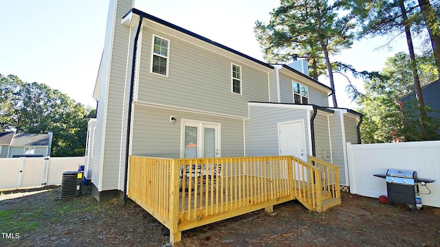rear view of house with a chimney, a wooden deck, fence, cooling unit, and a gate