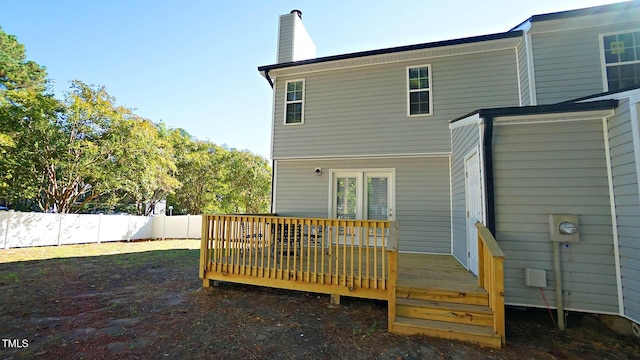 back of property featuring a deck, a fenced backyard, and a chimney
