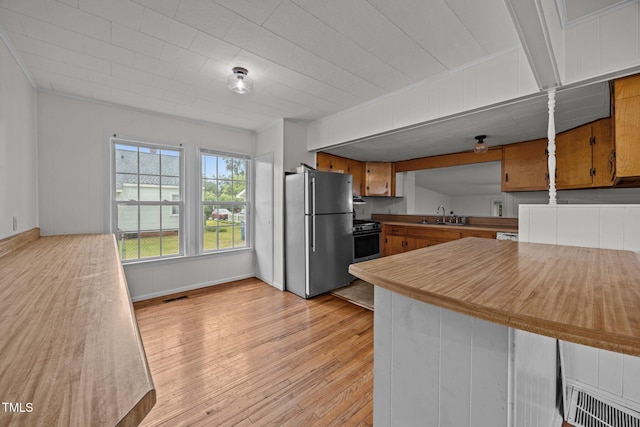 303 N Watauga Ave, Dunn, NC 28334 - kitchen with stainless steel appliances, light wood finished floors, a sink, brown cabinetry, and light countertops