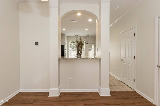 hallway featuring arched walkways, wood finished floors, recessed lighting, baseboards, and crown molding