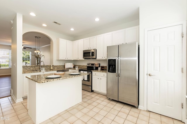 kitchen with appliances with stainless steel finishes, white cabinetry, a sink, light stone counters, and recessed lighting