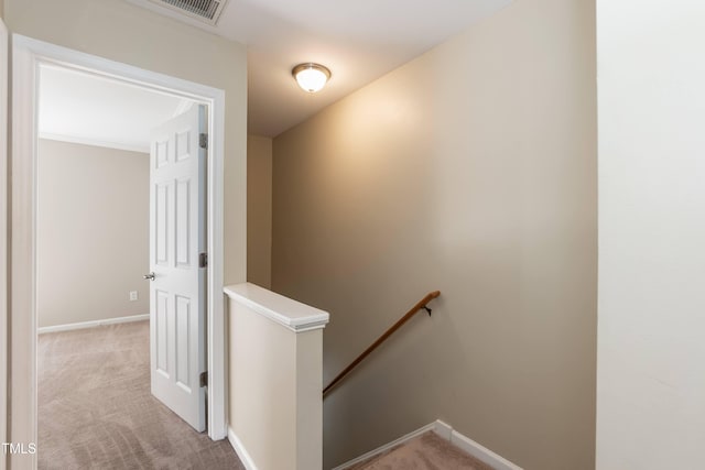 hallway with an upstairs landing, light carpet, and baseboards