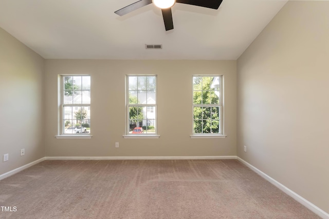 unfurnished room featuring healthy amount of natural light, carpet, and ceiling fan