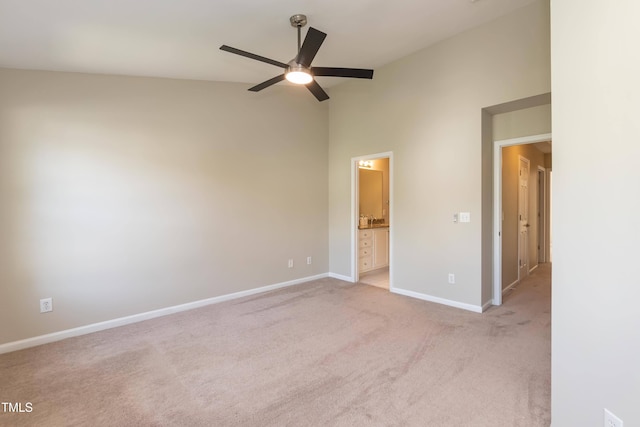 unfurnished bedroom with baseboards, light carpet, ensuite bathroom, a high ceiling, and ceiling fan
