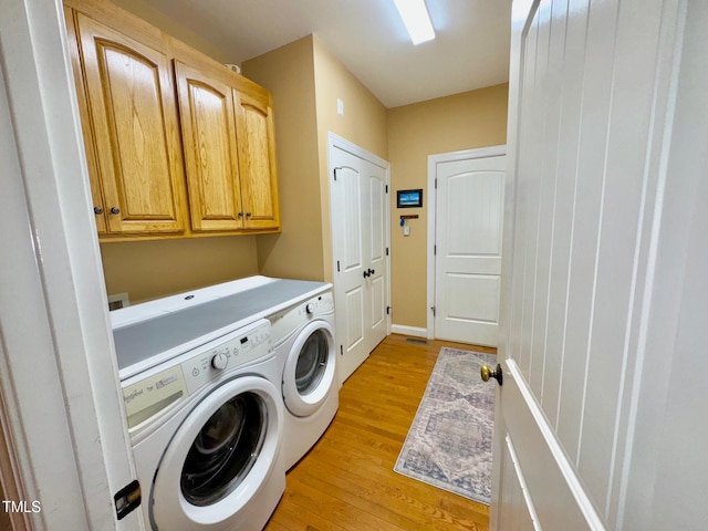 327 Beavertail Rd, Henderson, NC 27537 - washroom featuring washer and clothes dryer, cabinet space, light wood-style flooring, and baseboards