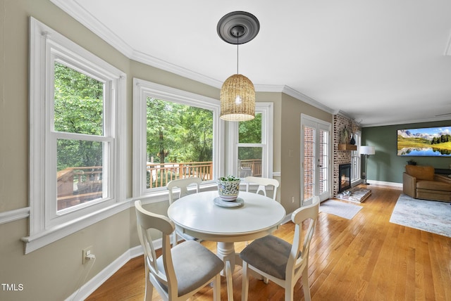 dining room with baseboards, light wood-style floors, ornamental molding, and a fireplace