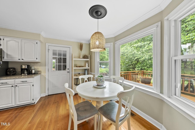 dining space featuring light wood-style flooring, ornamental molding, and baseboards