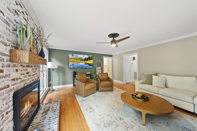 living room featuring wood finished floors, ornamental molding, baseboards, and ceiling fan