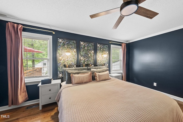 bedroom with ornamental molding, multiple windows, wood finished floors, a textured ceiling, and baseboards
