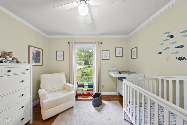 bedroom with dark wood-style flooring, crown molding, a crib, a textured ceiling, and ceiling fan