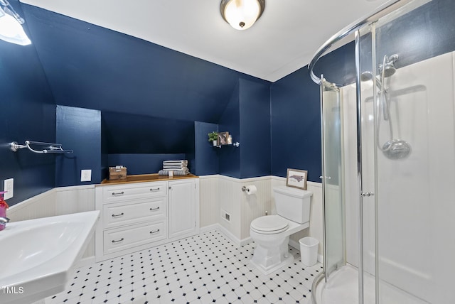 full bathroom featuring wainscoting, a shower stall, toilet, tile patterned flooring, and a bath