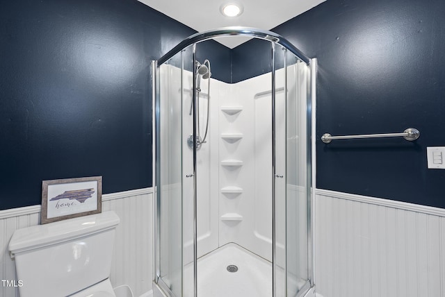 full bathroom with a wainscoted wall, a shower stall, and toilet