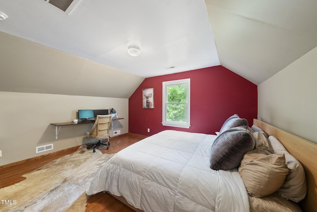 bedroom with wood finished floors and lofted ceiling