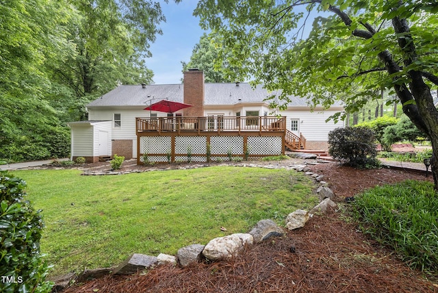 back of property featuring a deck, a lawn, and a chimney