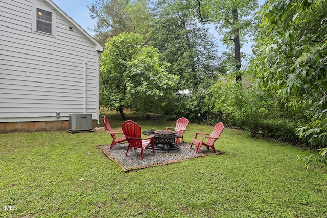 view of grassy yard with an outdoor fire pit and central air condition unit