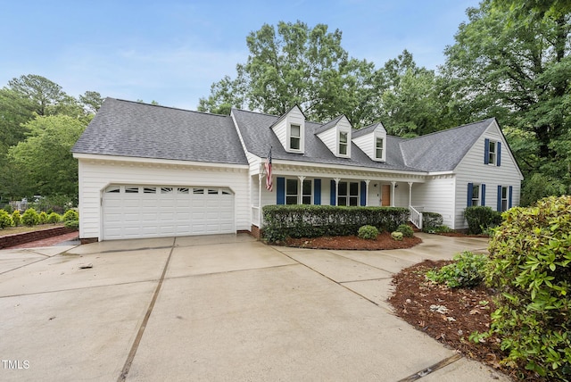 cape cod-style house with concrete driveway, a garage, a porch, and a shingled roof