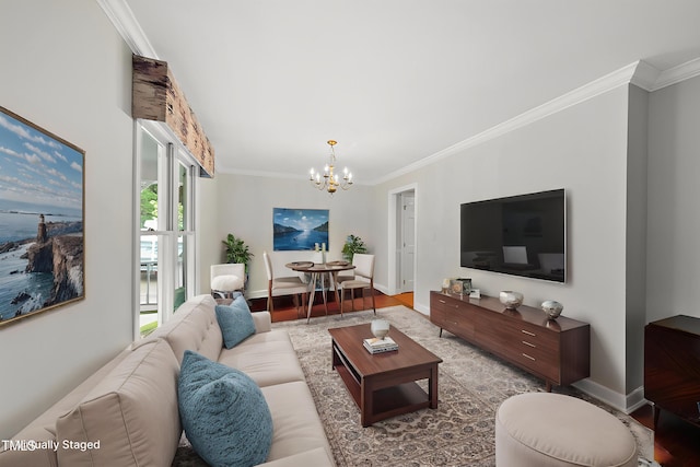 living room with a chandelier, ornamental molding, wood finished floors, and baseboards