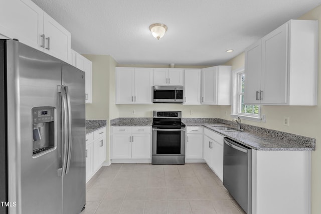kitchen with appliances with stainless steel finishes, a sink, light stone counters, white cabinetry, and recessed lighting