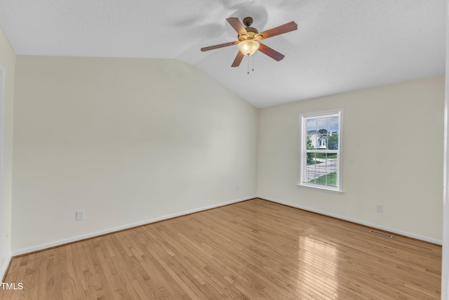 empty room with ceiling fan, vaulted ceiling, wood finished floors, and baseboards