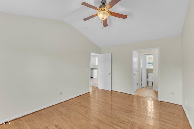 unfurnished bedroom with vaulted ceiling, light wood-type flooring, baseboards, connected bathroom, and ceiling fan