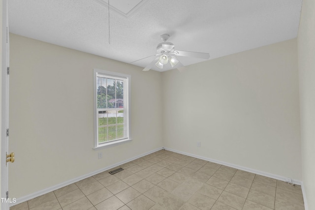 unfurnished room with attic access, a ceiling fan, baseboards, a textured ceiling, and light tile patterned floors