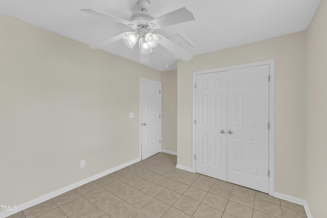 unfurnished bedroom featuring a closet, baseboards, light tile patterned floors, and a ceiling fan