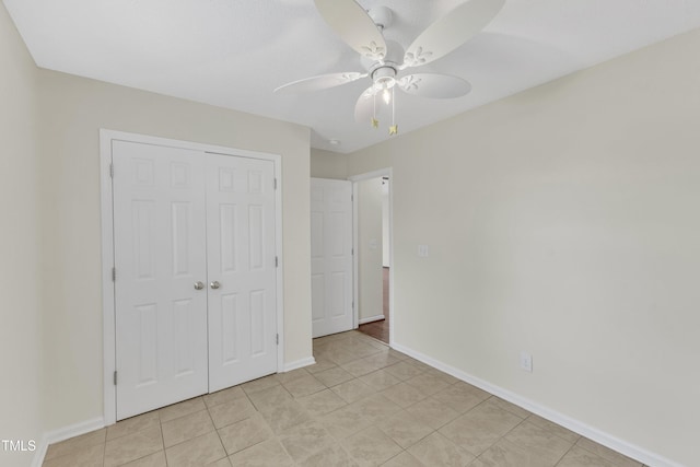 unfurnished bedroom featuring a closet, baseboards, light tile patterned floors, and a ceiling fan