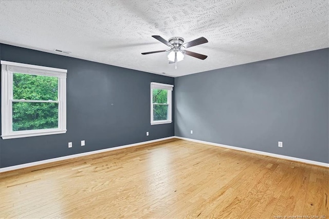 unfurnished room with wood finished floors, a textured ceiling, a ceiling fan, and baseboards
