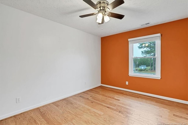 spare room with wood finished floors, baseboards, ceiling fan, and a textured ceiling