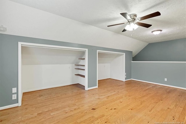 bonus room featuring a textured ceiling, vaulted ceiling, wood finished floors, ceiling fan, and baseboards