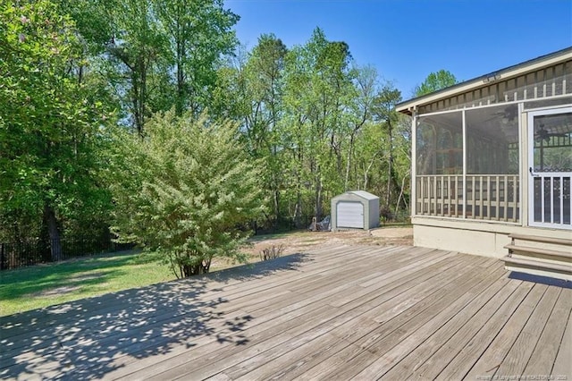 wooden terrace with a sunroom, a storage shed, and an outbuilding