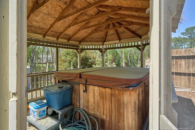 wooden deck with a hot tub, fence, and a gazebo