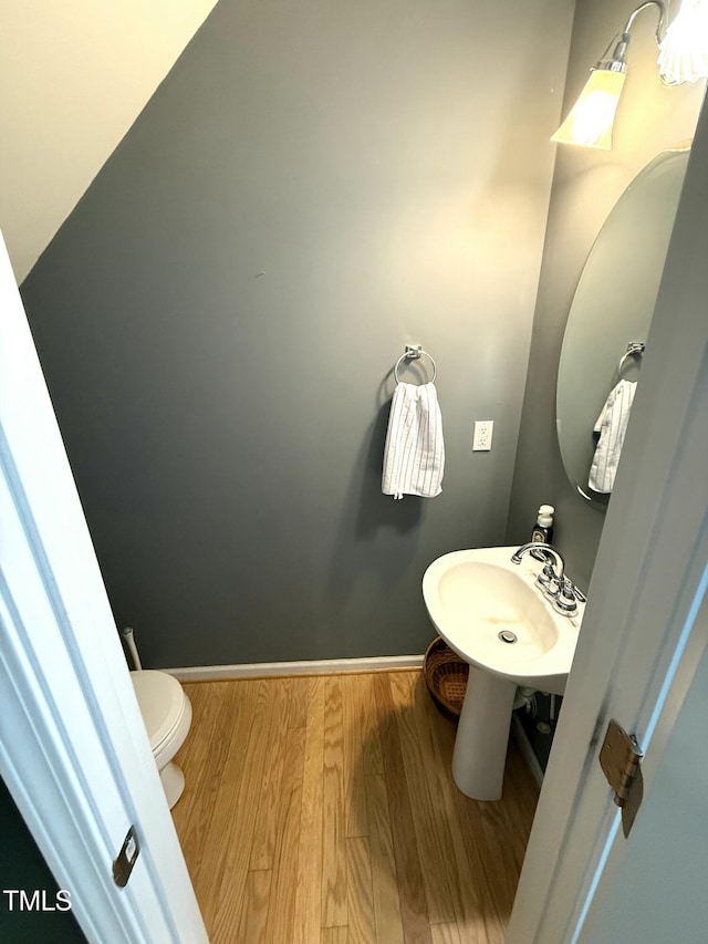 bathroom with wood finished floors, a sink, toilet, and baseboards