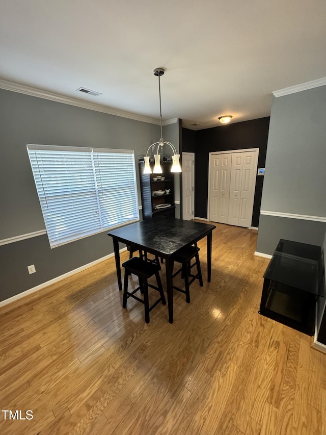 dining space featuring light wood-style floors, baseboards, a chandelier, and crown molding