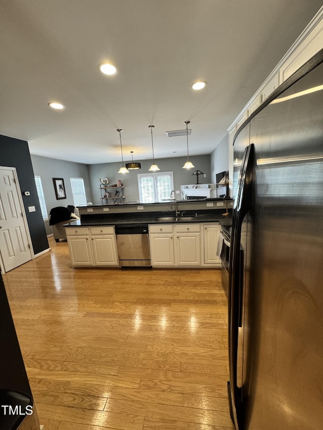 kitchen with stainless steel dishwasher, black fridge with ice dispenser, a sink, recessed lighting, and dark countertops